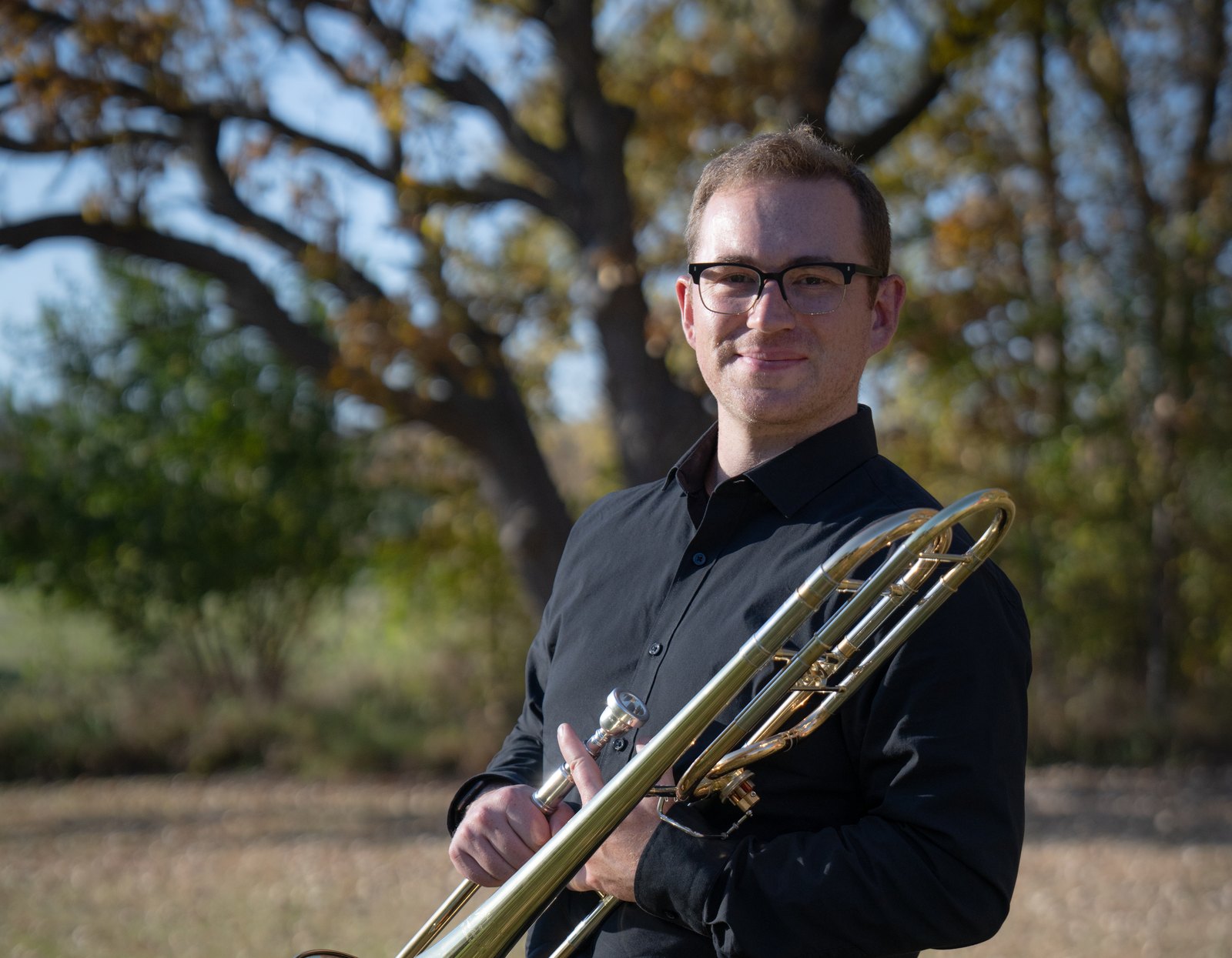 Christian Howard, trombonist and educator, holding a tenor trombone.